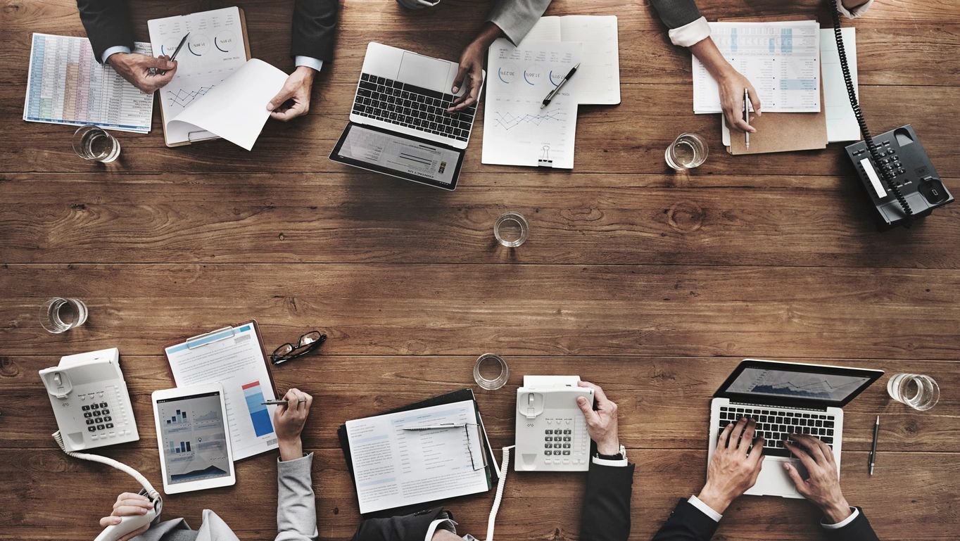 Business team analyzing financial reports on wooden table.